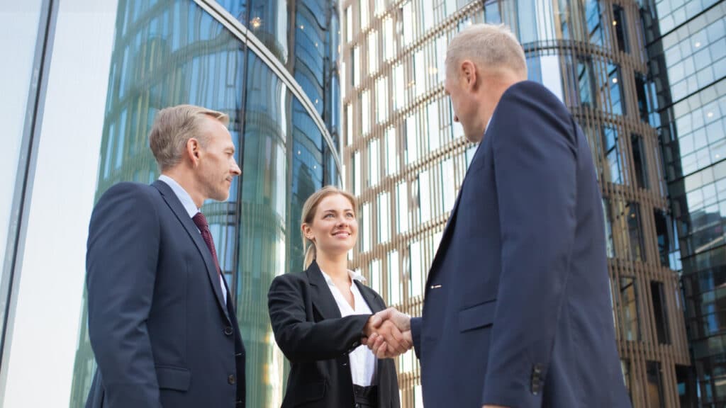 People standing in business attire in front of a building shaking hands